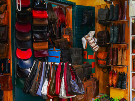 Colorful Western leather boots, studded handbags, backpacks fill artisan shop in Hoi An. A mannequin adds lifestyle appeal amid rustic textures, windows and boutique-style presentation. Vietnamの写真素材