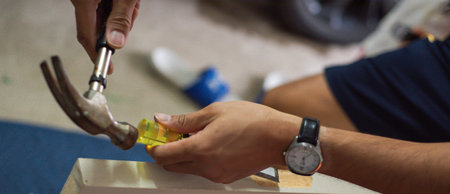 Panorama view yellow-handled chisel precisely guided by Asian craftsman into wood surface, shaping...