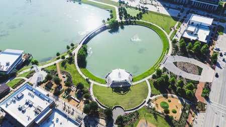 Aerial of circular pond with white pavilion, surrounded by office buildings, green trails, North...