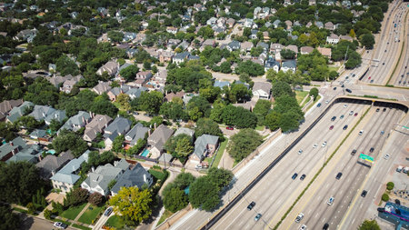 Row of two-story residential houses with backyard pools on narrow-lot grid along US 75 highway with...