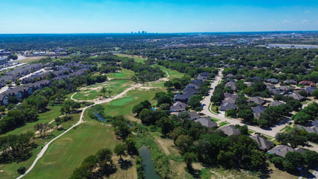 Golf course with creek and club car cart paths in North Richland Hills bordered by upscale homes, new apartments, office buildings, and warehouses, with Fort Worth skyline in background, Texas. USAの写真素材