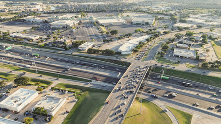 Peak-hour traffic along multilane highway in Lewisville, Texas with overpass and exit ramps, frontage roads, large strip mall in mid-ground, residential neighborhood grid in distant background. USAの写真素材