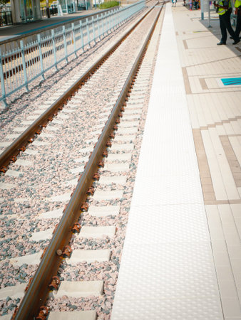 Passengers wait on clean, ADA-accessible platform near DFW Airport station. Concrete tiles, tactile...