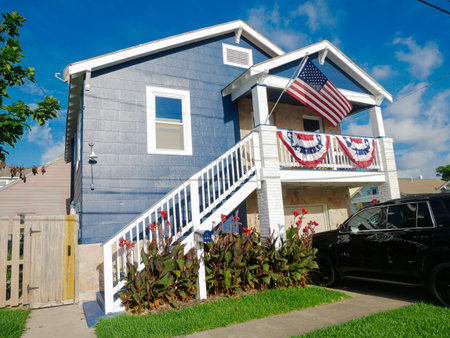 Single family home features white staircase, post column, and star-spangled bunting on upper balcony, blending Southern elevation with patriotic flair in sunny coastal setting, Galveston, Texas. USAの写真素材