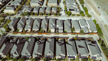 Multiple rows of two-story single-family homes in uniform gray pitched roofs, symmetrical driveways, fenced backyards, large boulevard, showcasing precise suburban grid planning, Flower Mound, TX. USAの写真素材