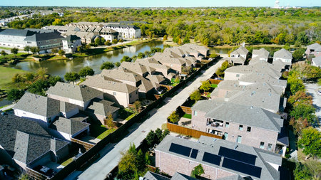 Rows of single-family homes with gabled roofs, narrow lot, bordered by pond with fountains, tree-lined surroundings, highlighting suburban density and water feature integration, Flower Mound, TX. USAの写真素材