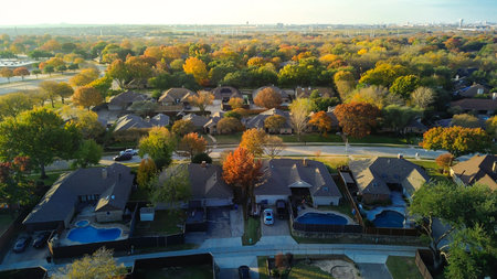 Distant Dallas city water towers, skyline visible beyond Coppell vivid autumn foliage neighborhoods,...