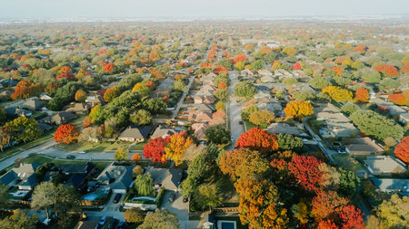 Residential neighborhoods framed by autumn foliage stretching across rooftops and streets,...