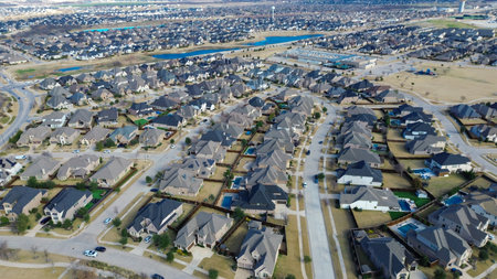 Scenic ponds and creek from grid-like suburban layout with curved streets, fenced yards, pools. Uniform rooflines, parked vehicles reflect planned density, architectural consistency, Prosper, TX. USAの写真素材