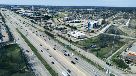 Busy highway lanes run along US 75 near E Spring Creek Pkwy with commercial buildings, residential...