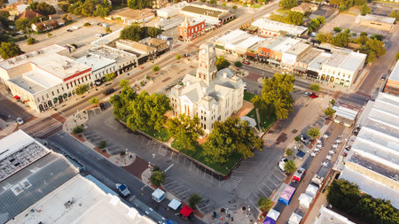 Courthouse festival square captures Hood County historic downtown centered within Granbury Square as vendor tents, commercial blocks line Houston St, Bridge St with stone walls, flat rooftops, TX. USA