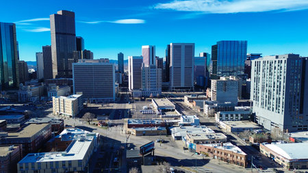 Skyscrapers dominate horizons over Five Points near intersection of Park Avenue Welton Street. Bright morning solar rays highlight sharp glass facades barren winter branches in Denver, CO. USA