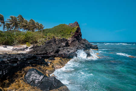 Tropical beach with turquoise water and volcanic rocks.