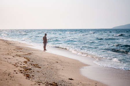 A person in a swimsuit walks along the seashore.の写真素材