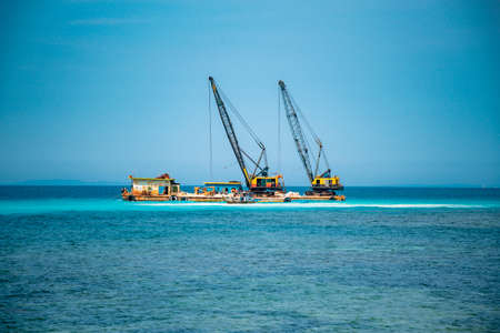 Cargo ships on the roads, coastline. Bright blue sky, sunny day.