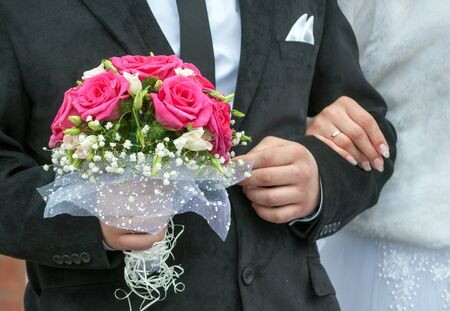 The hand of the groom holds a bouquetの写真素材