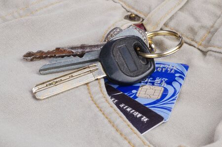 The keys and credit cards in the pocket of bright jeans close up