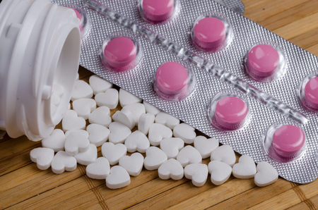 Pink and white pills in the form of heart close upの写真素材