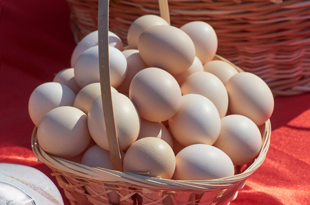 Chicken eggs in a wicker basket on red outdoorの写真素材