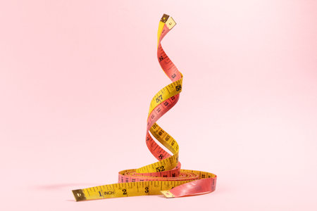 Pink and yellow measuring tape on pink background