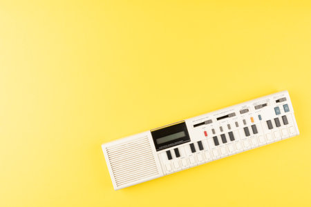 Vintage electronic keyboard synth piano on yellow backgroundの写真素材