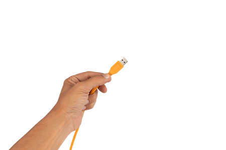 Male hand holding an orange usb cable isolated on white backgroundの写真素材