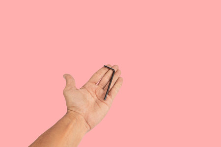 Black male hand offering an allen key isolated on pink backgroundの写真素材