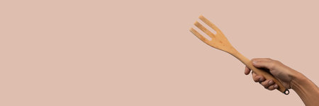 Hand holding wooden fork on dark pink background, cutoutの写真素材