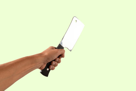 Hand holding a butcher knife isolated on green backgroundの写真素材