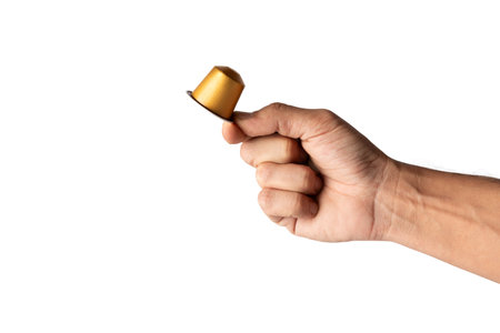 Male hand holding a golden coffee capsule isolated on white background cutoutの写真素材