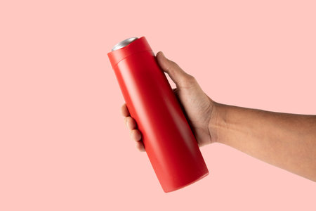 Hand holding a red bottle isolated on pink backgroundの写真素材