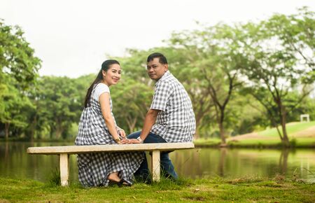 Portrait of asian young couple in love sitting  near lake in the park  .の写真素材