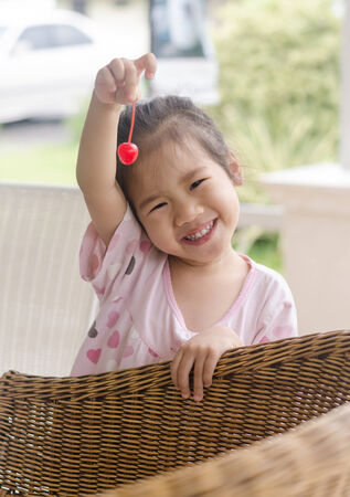 Asian young girl showing a cherry fruit to her mom in cafe.の写真素材