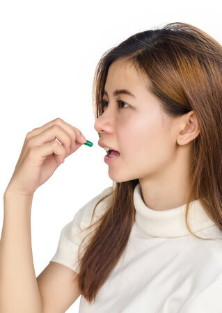Beautiful asian woman holding a pill against white background.の写真素材
