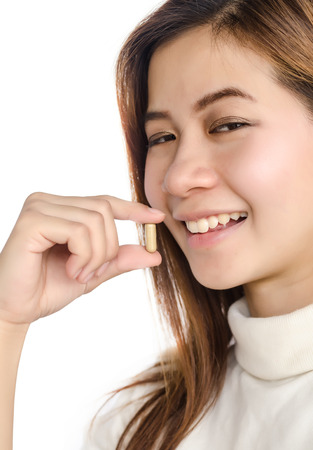 Beautiful asian woman holding a pill against white background.の写真素材