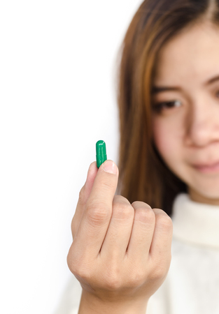 Beautiful asian woman holding a pill against white background.の写真素材