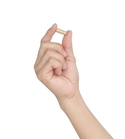 Hand of a woman holding a pill against white background.の写真素材