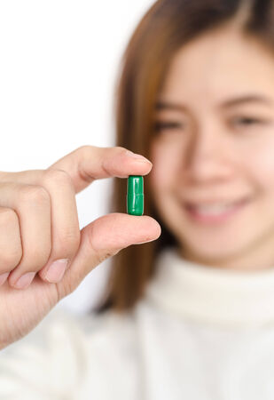 Beautiful asian woman holding a pill against white background.の写真素材