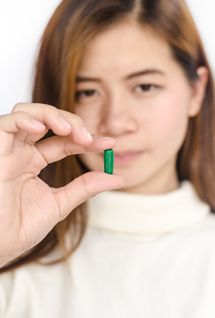 Beautiful asian woman holding a pill against white background.の写真素材