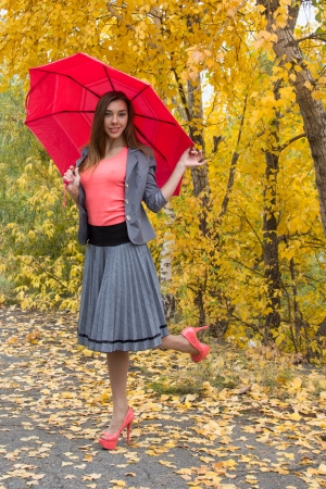 Happy woman outdoor in autamn with red umbrellaの写真素材