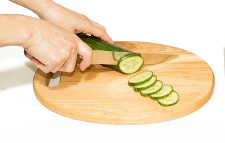 Cucumber cutting on the wooden board. Isolated on white.の写真素材