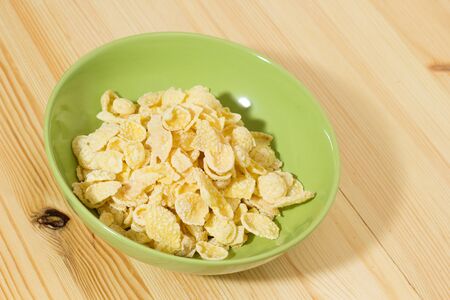 A bowl of Corn flakes on wooden table