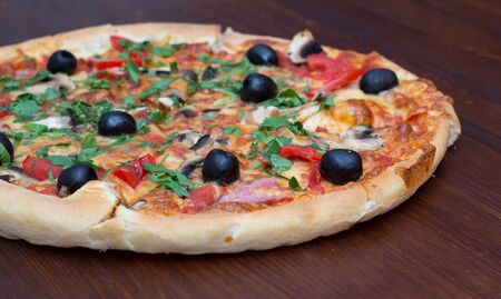 Pizza with mashrooms and chiken and olives on a wooden boardの写真素材