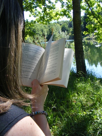 adult woman reading a book surrounded by nature in the open airの写真素材