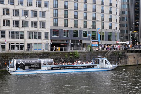 BERLIN, GERMANY - JULY 25, 2015: Exterior view of buildings and a boat shipping at the river Spree in Berlin on July 25, 2015 - Germany. The Spree is a river that flows through Berlin.のeditorial素材