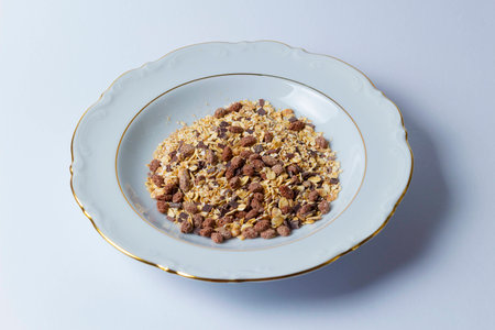 Chocolate muesli on white plate against white backgroundの写真素材