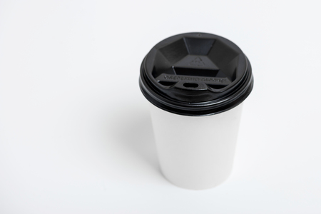 One focused take away white paper cup with black cap presented in front, isolated on simple gray backgroundの写真素材