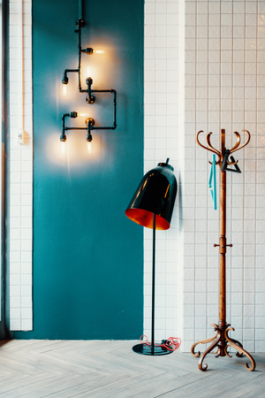 Interior with bed, blankets, garland and Edison lamps. Light colors, large window and blue wall copy spaceの写真素材