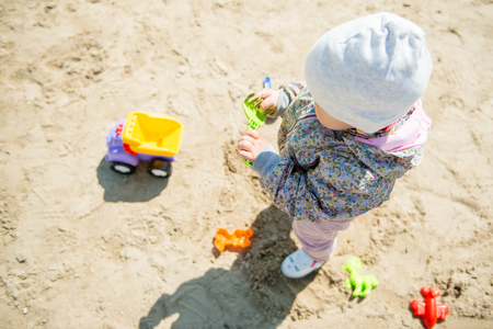 Toddler girl playing in sand on the beach in spring or autumn, leisure activityの写真素材