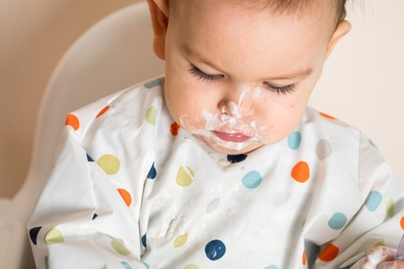 A Little baby eating her dinner and making a mess